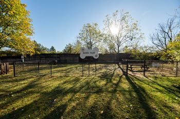 a fenced in dog park with the sun shining through the trees at Indian Creek Apartments*, Cincinnati, OH